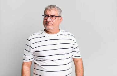 Orta yaşlı bir adam kafası karışmış ve kafası karışmış görünüyor. Bir sorunu çözmeye çalışıyor ya da düşünüyor.
