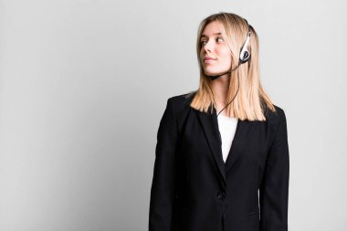 Profil görünümlü genç, güzel bir kadın hayal kuruyor ya da hayal kuruyor. tele pazarlamacı kavramı