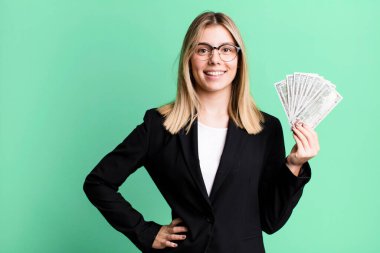 young pretty woman smiling happily with a hand on hip and confident. business and money concept