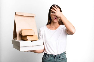 Genç, güzel bir kadın şok olmuş, korkmuş ya da korkmuş görünüyor. teslimat ve paket konsepti