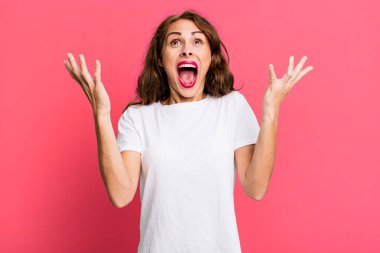 Genç, güzel bir kadın kendini mutlu, şaşkın, şanslı ve şaşırmış hissediyor. Zaferi kutlarken iki elini de havaya kaldırıyor.