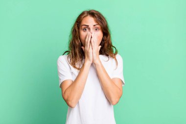 Genç, güzel bir kadın endişeli, üzgün ve korkmuş hissediyor. Ağzını ellerle kapatıyor. Endişeli ve berbat görünüyor.