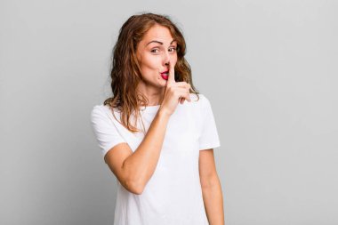 Genç ve güzel bir kadın sessizlik ve sessizlik istiyor, parmaklarıyla ağzının önünde işaret ediyor, 