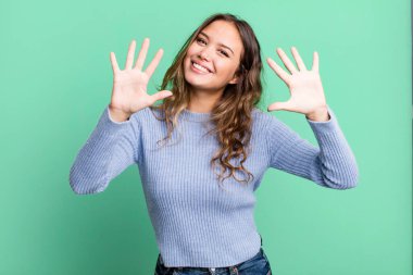 Genç ve güzel bir bayan gülümsüyor ve arkadaş canlısı görünüyor, onuncu veya onuncu numarayı gösteriyor, eli önde, geriye doğru sayıyor.