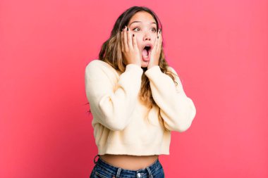 Genç, güzel bir kadın mutlu, heyecanlı ve şaşırmış hissediyor. İki eli de havada bir tarafa bakıyor.