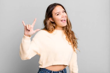 Genç, güzel bir kadın kendini mutlu, eğlenceli, kendinden emin, pozitif ve asi hissediyor, elle rock ya da heavy metal işareti yapıyor.