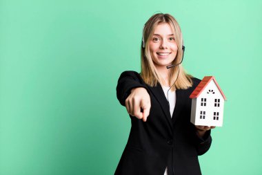 Kulaklığı ve ev modeliyle genç ve güzel bir kadın. gerçek durum kavramı