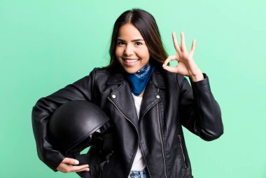 İspanyol güzel kadın kendini mutlu hissediyor, iyi bir jestle onaylıyor. Motosiklet sürücüsü konsepti