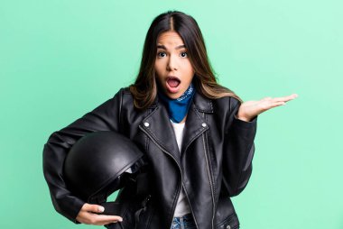 İspanyol güzel kadın şaşırmış ve şok olmuş görünüyor. Çenesi düşmüş ve elinde bir nesne var. Motosiklet sürücüsü konsepti