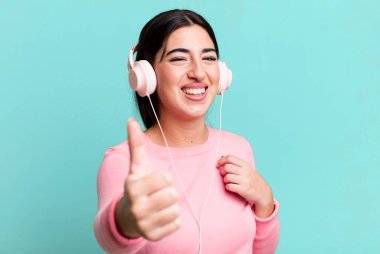 feeling proud,smiling positively with thumbs up. listening music with headphones