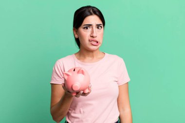 looking puzzled and confused. with a piggy bank