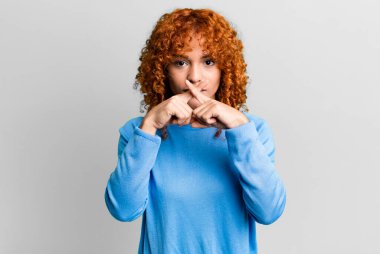 Kızıl saçlı, güzel bir kadın ciddi görünüyor ve iki parmağının önde olması hoşuna gitmiyor. Reddedilmek için, sessizlik istiyor.