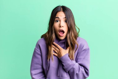 İspanyol güzel kadın şaşkın ve şaşırmış hissediyor, gülümsüyor, el ele tutuşuyor, mutlu ya da minnettarlık gösteriyor.