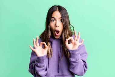 İspanyol güzel kadın şok olmuş, şaşırmış ve şaşırmış hissediyor. Onaylıyor. İki eliyle işaret veriyor.