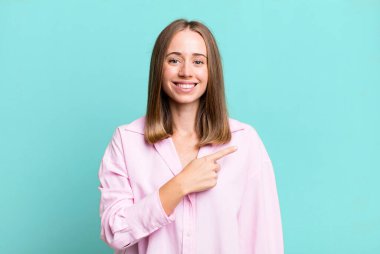 Neşeli bir şekilde gülümseyen, mutlu hisseden, kenarı ve yukarıyı gösteren, kopya uzayda nesneleri gösteren