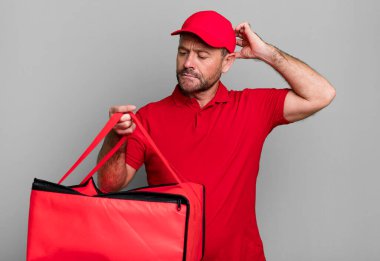 Orta yaşlı bir adam mutlu bir şekilde gülümsüyor ve hayal kuruyor ya da şüphe ediyor. Pizza teslimatçısı.