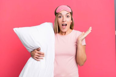 pretty blonde woman feeling happy and astonished at something unbelievable. pajamas or nightwear concept