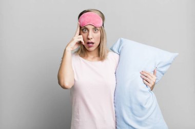 pretty blonde woman looking surprised, realizing a new thought, idea or concept. pajamas and nightwear concept
