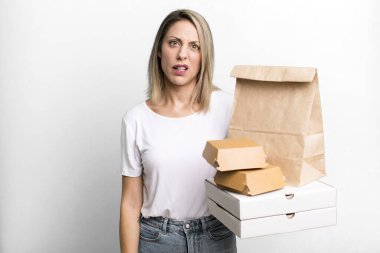 pretty blonde woman feeling puzzled and confused. paper fast food take away packages