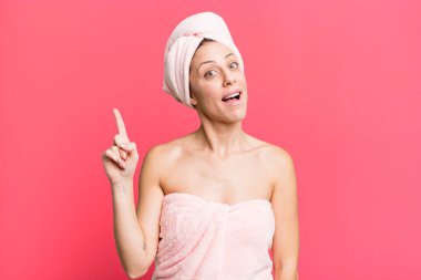 pretty blonde woman feeling like a happy and excited genius after realizing an idea. bathrobe and beauty concept