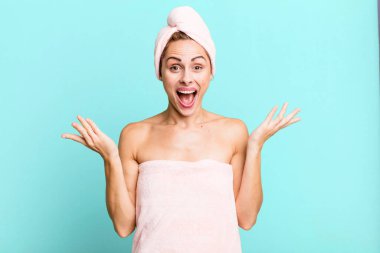 hispanic pretty woman feeling happy and astonished at something unbelievable wearing pbathrobe. beauty concept