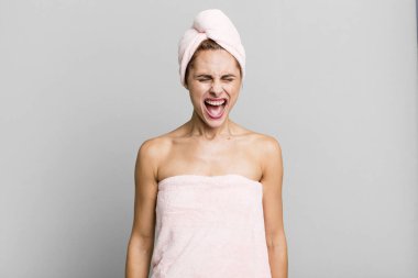 hispanic pretty woman shouting aggressively, looking very angry wearing pbathrobe. beauty concept