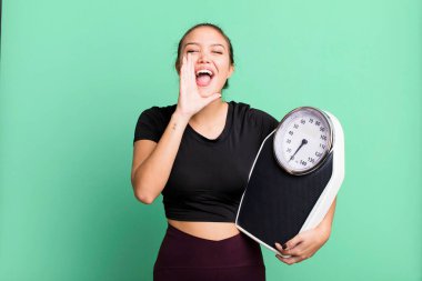 hispanic pretty woman feeling happy,giving a big shout out with hands next to mouth. fitness and diet concept