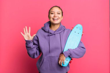 hispanic pretty woman smiling and looking friendly, showing number five. skate boarding concept