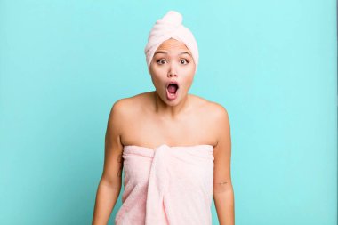hispanic pretty woman looking very shocked or surprised wearing bathrobe. beauty concept