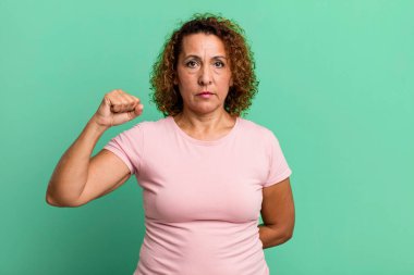 Orta yaşlı İspanyol kadın kendini ciddi, güçlü ve asi hissediyor, yumruğunu kaldırıyor, protesto ediyor ya da devrim için savaşıyor.