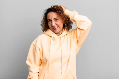 Orta yaşlı İspanyol kadın neşeli ve rahat bir şekilde gülümsüyor, olumlu, mutlu ve kendinden emin bir bakışla yumruk yumruğa.