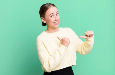 Neşeli bir şekilde gülümsüyor ve yan taraftaki fotokopi alanını işaret ediyor, mutlu ve tatmin olmuş hissediyordu.