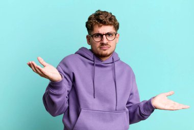 young adult caucasian man looking puzzled, confused and stressed, wondering between different options, feeling uncertain
