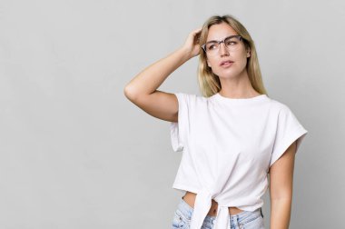 caucasian blonde woman feeling puzzled and confused, scratching head. copy space concept