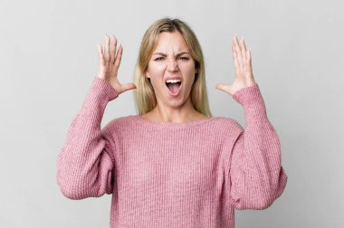 caucasian blonde woman screaming with hands up in the air
