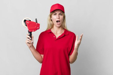 caucasian blonde woman feeling extremely shocked and surprised. shipping packer concept