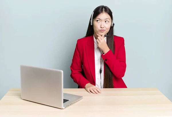pretty asian woman thinking, feeling doubtful and confused. business desk concept