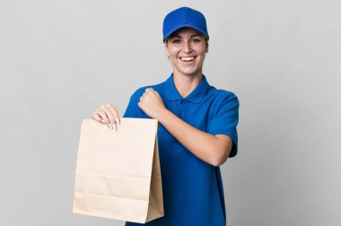 caucasian blonde woman feeling happy and facing a challenge or celebrating. paper bag delivery concept