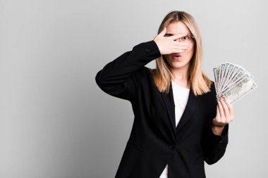young pretty woman looking shocked, scared or terrified, covering face with hand. business and money concept