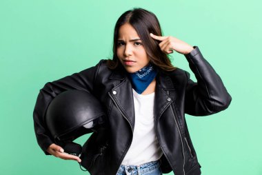 hispanic pretty woman feeling confused and puzzled, showing you are insane. motorbike rider concept