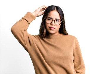 İspanyol güzel kadın şaşkın ve şaşkın hissediyor, başını kaşıyor ve yana bakıyor.