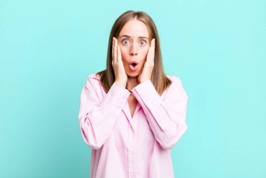 Kötü bir şekilde şoke olmuş, korkmuş ya da endişeli, ağzı sonuna kadar açık ve iki kulağını da eliyle kapatmış.