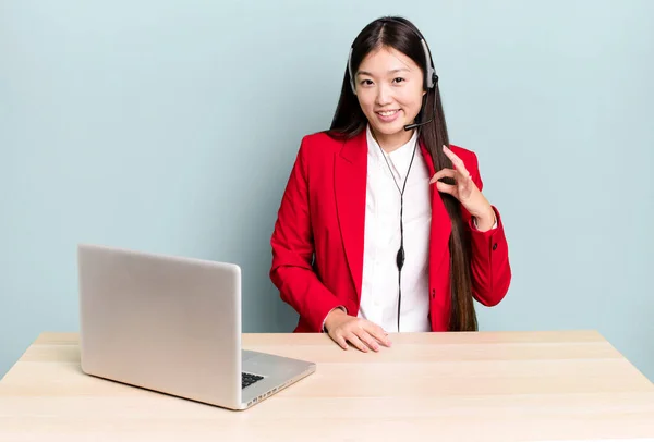 pretty asian woman looking arrogant, successful, positive and proud. business desk concept