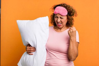 pretty middle age woman looking unhappy and stressed, suicide gesture making gun sign wearing pajamas night wear and a pillow