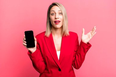pretty blonde woman feeling happy, surprised realizing a solution or idea. businesswoman showing a phone screen