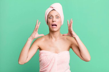 pretty blonde woman screaming with hands up in the air. bathrobe and beauty concept