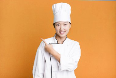 Güzel Asyalı kadın neşeyle gülümsüyor, mutlu hissediyor ve bir tarafı işaret ediyor. restoran şefi konsepti