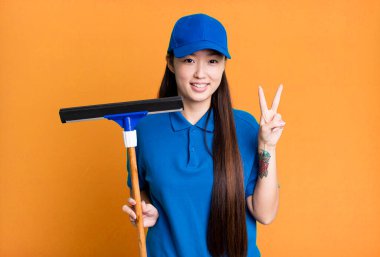 Güzel Asyalı kadın gülümsüyor ve arkadaş canlısı görünüyor, iki numarayı gösteriyor. pencere temizleme kavramı