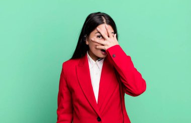 hispanic pretty woman looking shocked, scared or terrified, covering face with hand. telemarketing concept