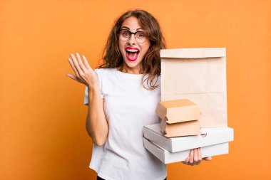 İspanyol güzel kadın kendini mutlu hissediyor ve inanılmaz bir şeye hayret ediyor. Fast food paketleri kavramını kaldır